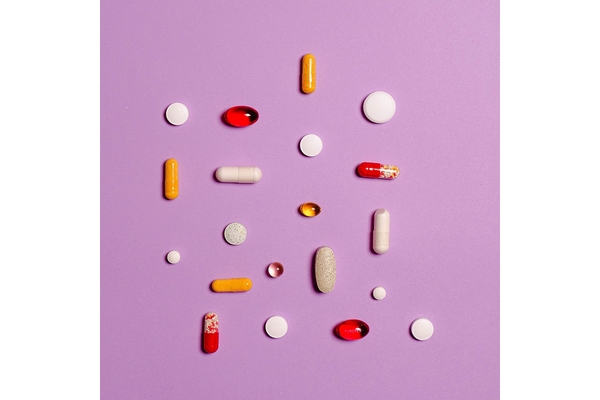 Image Lots of pretty colored pills on a lavender background.
